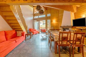 Ein Holzinnenraum mit Treppe, einem orangefarbenen Sofa, einem Esstisch und Stühlen.