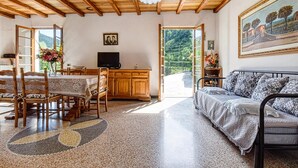 A cozy living room with a wooden ceiling, a dining area with a table and chairs, a sofa, and a television. - 2 bedroom lovely home in Ne (Ne)