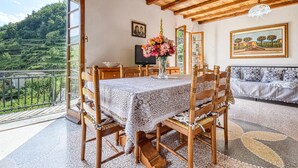 A dining area with a table set for two, wooden chairs, a vase of flowers, and a television on a wooden cabinet. - 2 bedroom lovely home in Ne (Ne)