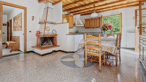 A cozy room with a fireplace, wooden furniture, a dining table with chairs, and a kitchen area. - 2 bedroom lovely home in Ne (Ne)