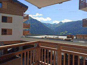 En balkon med trægelænder med udsigt over et bjerglandskab.