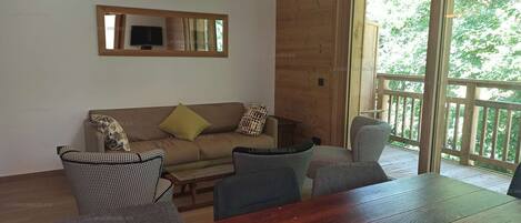Un intérieur en bois comprenant un canapé, des fauteuils, une table et un téléviseur.