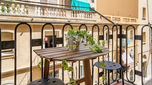 A balcony with a wooden table, metal chairs, and a potted plant. - MEDITERRANEO 2 APARTMENT (Barcelona)