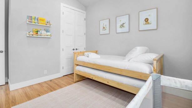 A bedroom with a wooden bunk bed, a white door, and a shelf with children's books. - 4 Bedroom Luxury in Capitola Village w/ parking! (Capitola)