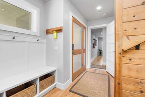 A hallway with a white bench, wooden door, and a small shelf with baskets. - 4 Bedroom Luxury in Capitola Village w/ parking! (Capitola)