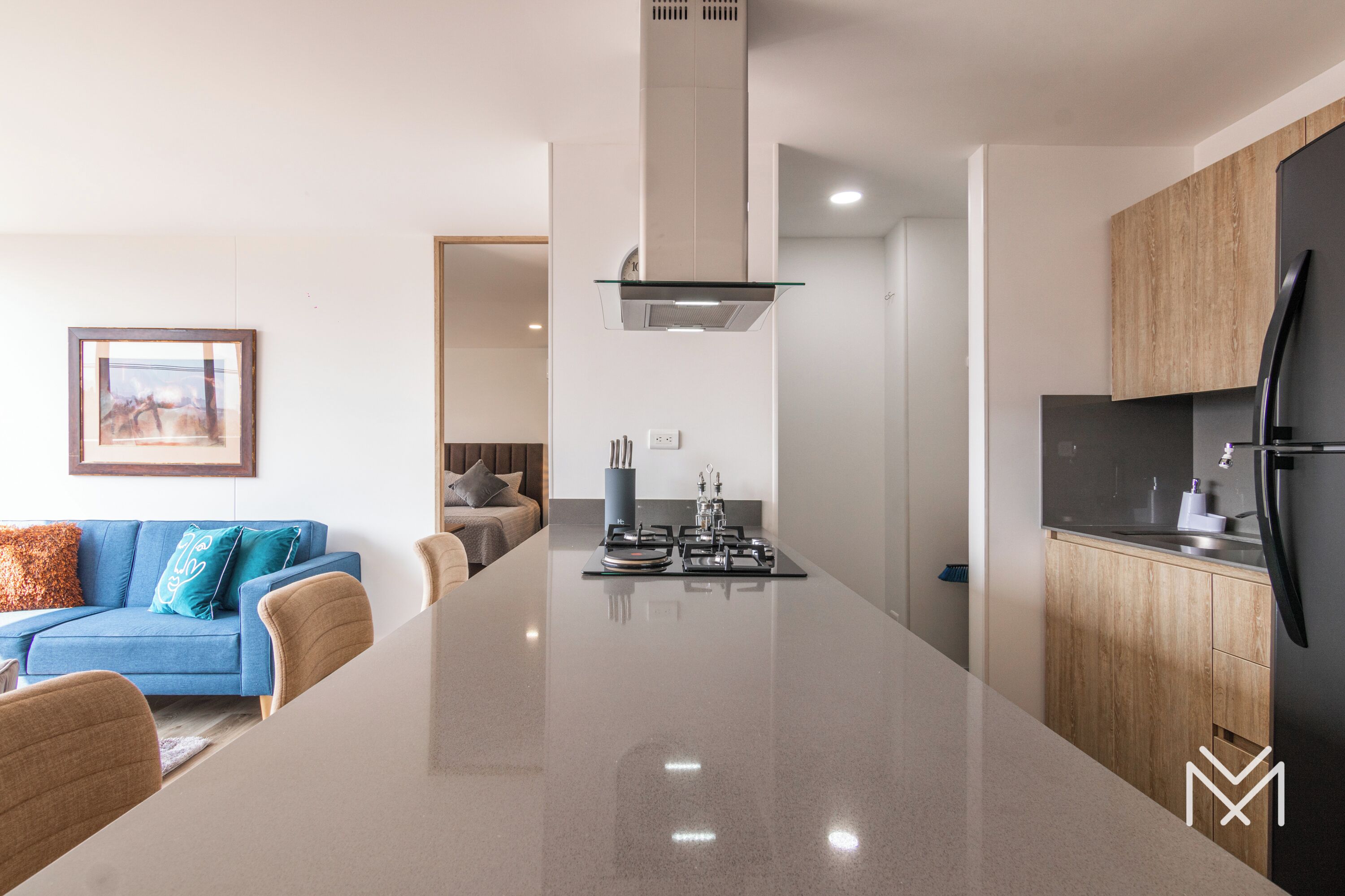 A modern kitchen with a central island, wooden cabinets, and a black refrigerator.