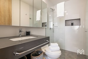 Un baño moderno con un espejo grande, un lavamanos y un inodoro.