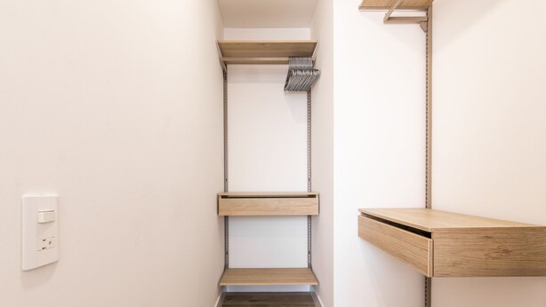 Een smalle badkamer met een inloopdouche, een houten plank en een klein houten kastje.