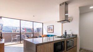 Una cocina moderna con una isla grande, horno empotrado y microondas. Hay un comedor con vistas a la ciudad y a las montañas.