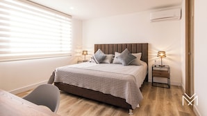 Un dormitorio con cama, mesitas de noche, escritorio y silla.
