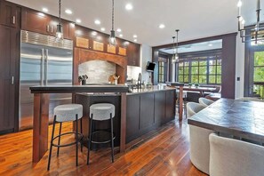 Une cuisine moderne dotée d’un îlot central, de tabourets de bar et d’une grande fenêtre.