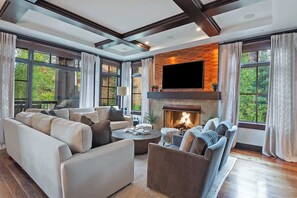 Una sala de estar moderna con chimenea, ventanas amplias y un televisor de pantalla plana.