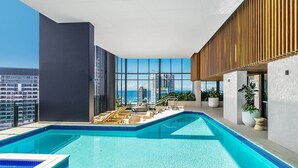 Une piscine à débordement située sur le toit, avec des chaises longues et une vue imprenable sur les toits de la ville.