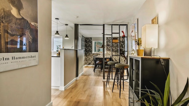 Una cocina moderna con suelo de madera, una zona de comedor con taburetes y un refrigerador negro.