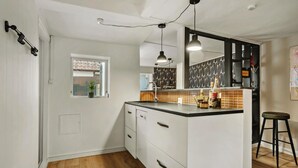 Una cocina moderna con armarios blancos, encimera negra, ventana con vistas y una lámpara colgante.