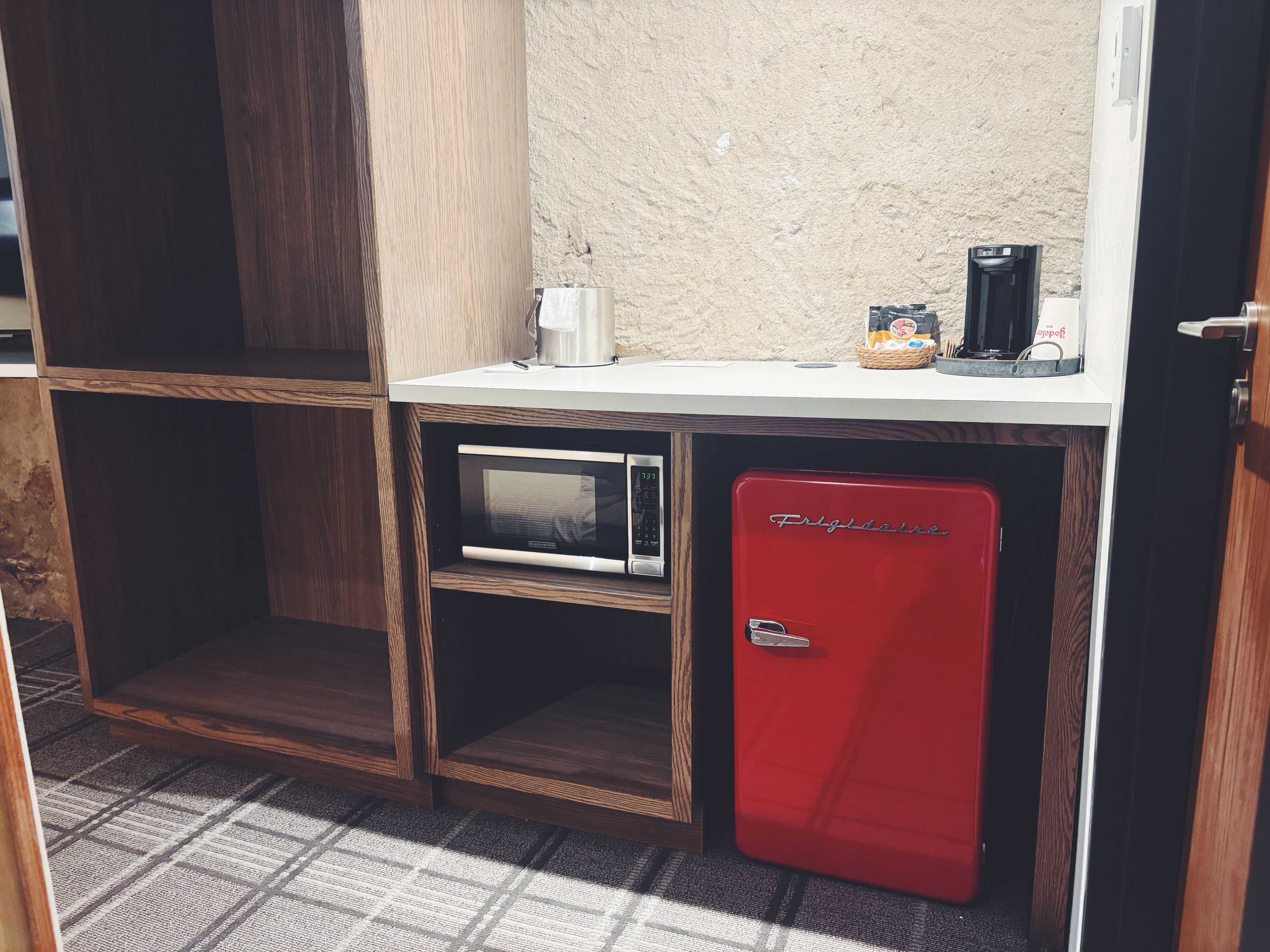 A compact kitchenette with a microwave, a red mini-fridge, and a coffee maker on the counter.