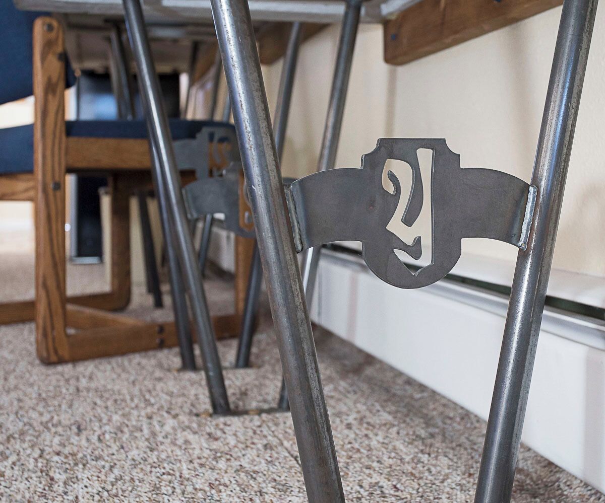 Ein Metallstuhl mit der Nummer 2, Teil eines Raumes mit Teppichboden und Holzmöbeln.
