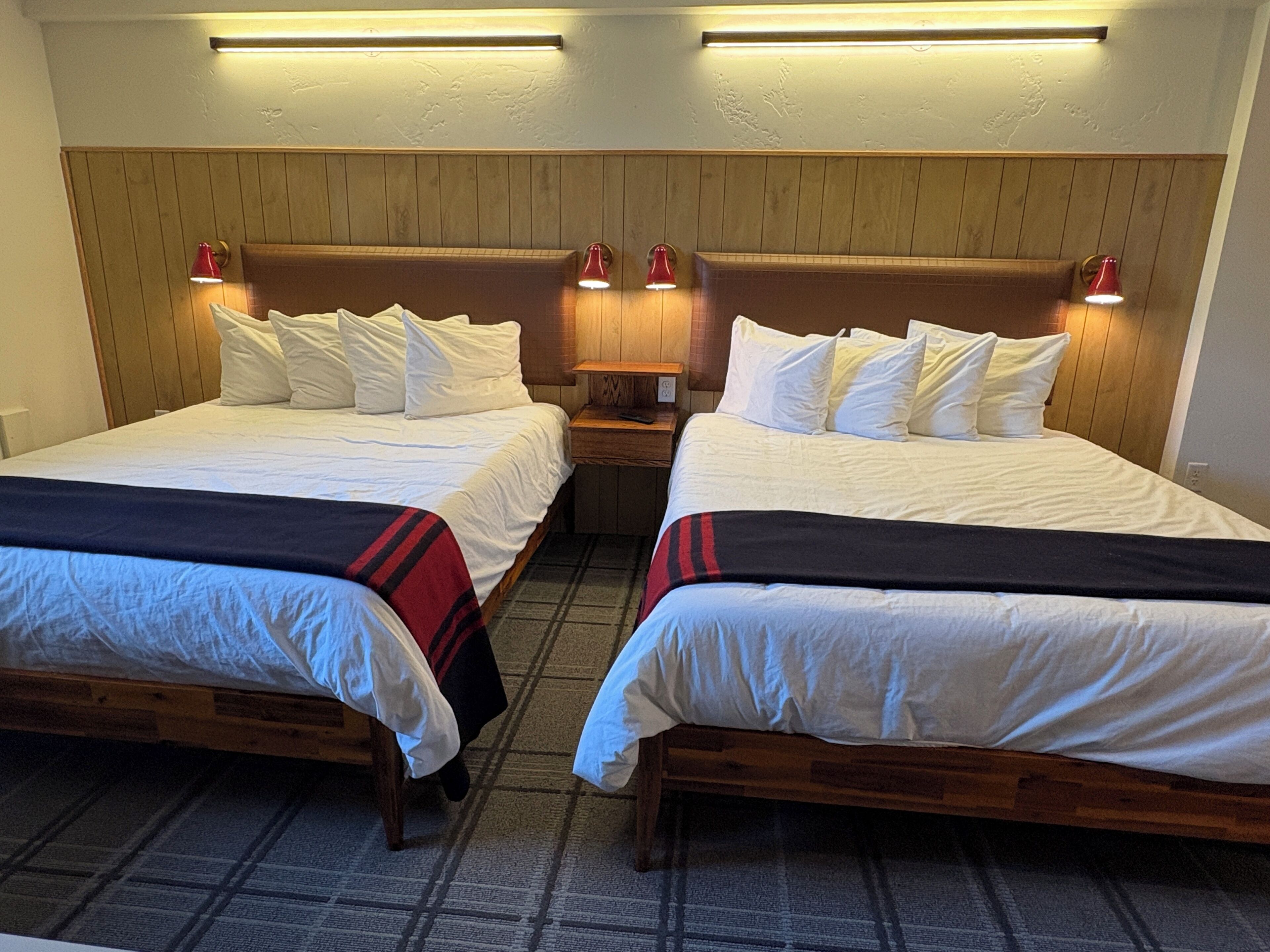 A hotel room with two beds, wooden headboards, and bedside lamps.