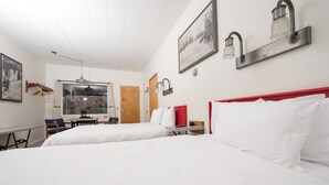 A hotel room with two beds, a desk, a chair, and a window with a view. - Yodeler Motel (Red Lodge)