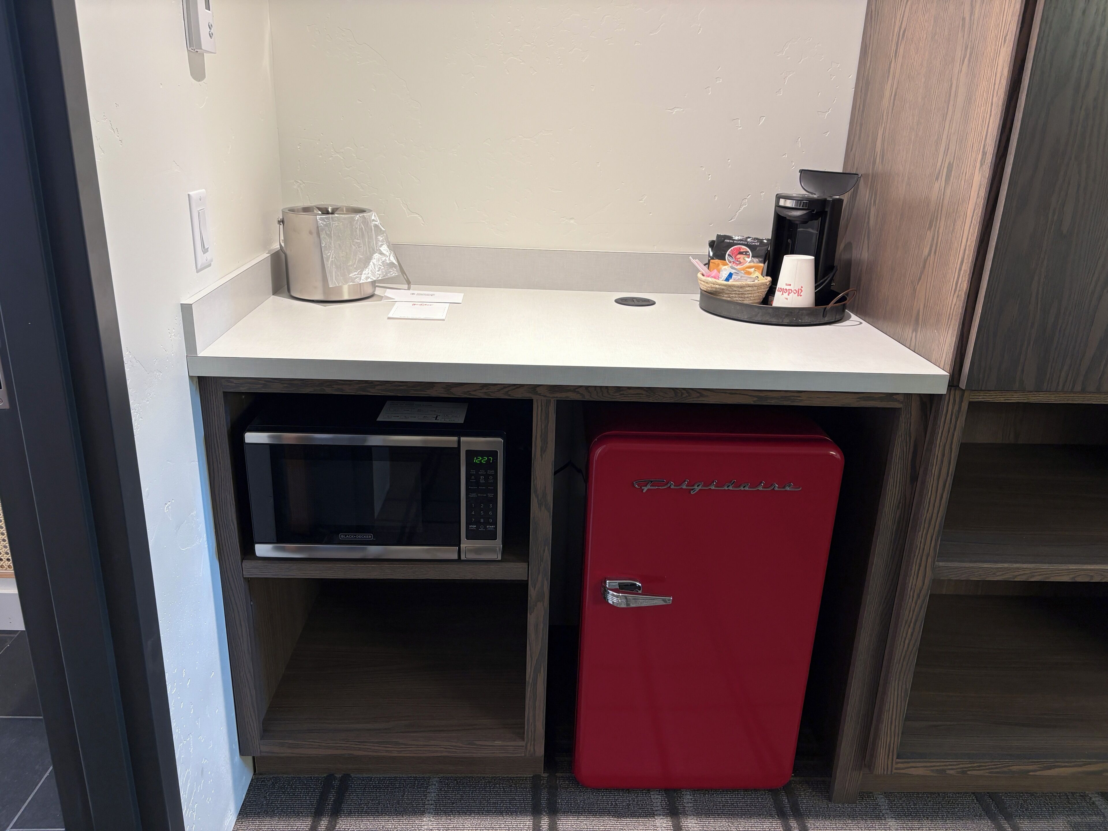 A kitchenette with a microwave, a red mini-fridge, a coffee maker, and a small countertop.