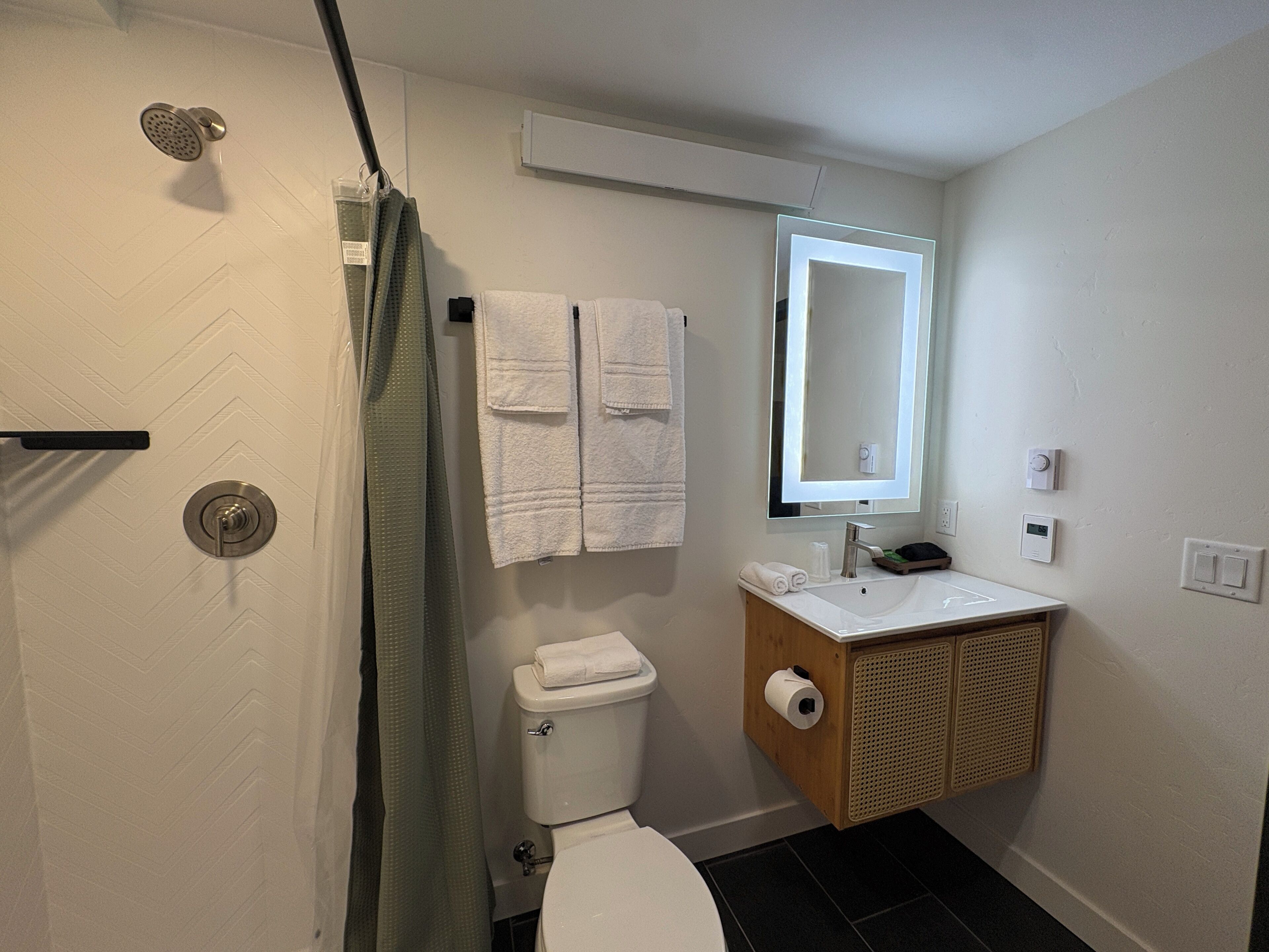 A bathroom with a shower, toilet, sink, and a mirror.