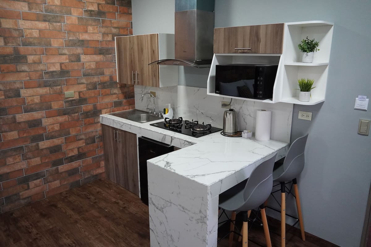 A compact kitchen with a marble countertop, a gas stove, a microwave, and wooden cabinets.