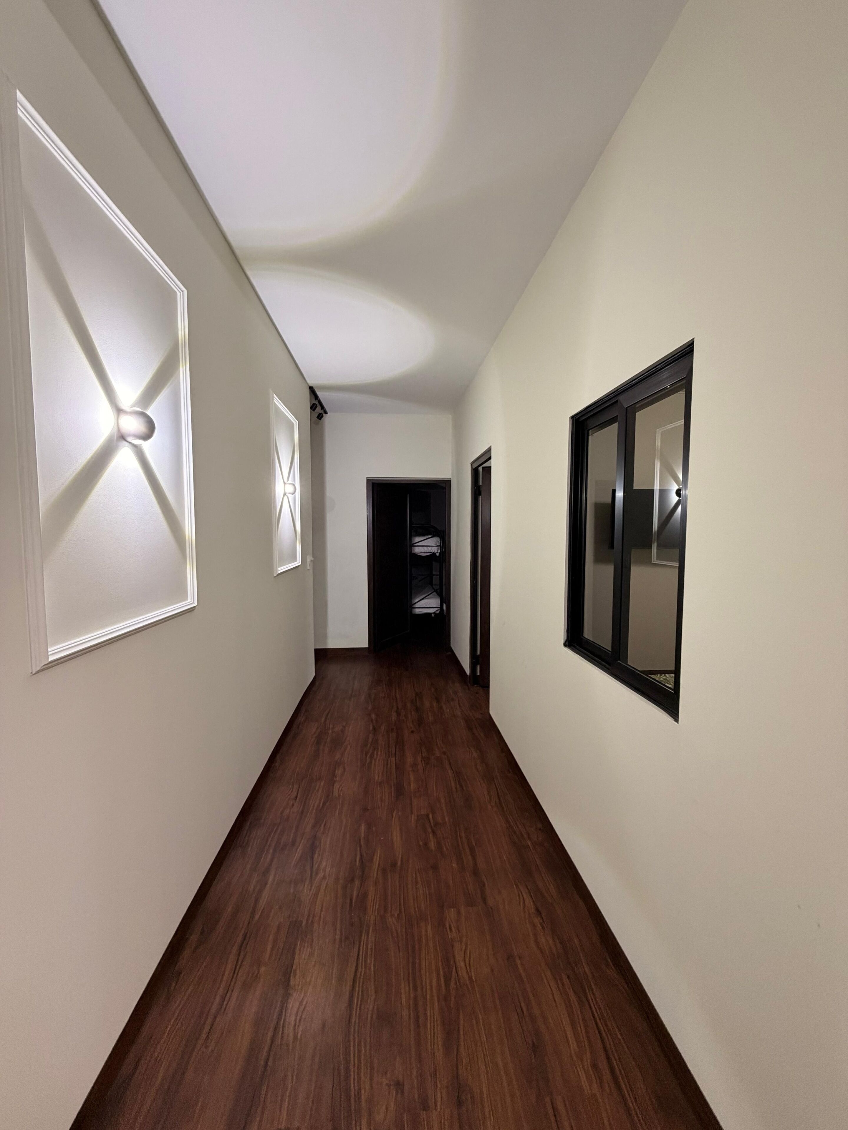 A hallway with wooden flooring, white walls, and a ceiling with recessed lighting.
