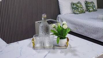 A marble table with a glass bottle, a glass carafe, and a potted plant with white flowers.