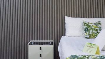 Quarto de hotel com uma cama, uma mesinha de cabeceira e uma parede com linhas verticais.
