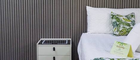 Une chambre d’hôtel avec un lit, une table de chevet et un mur orné de lignes verticales.