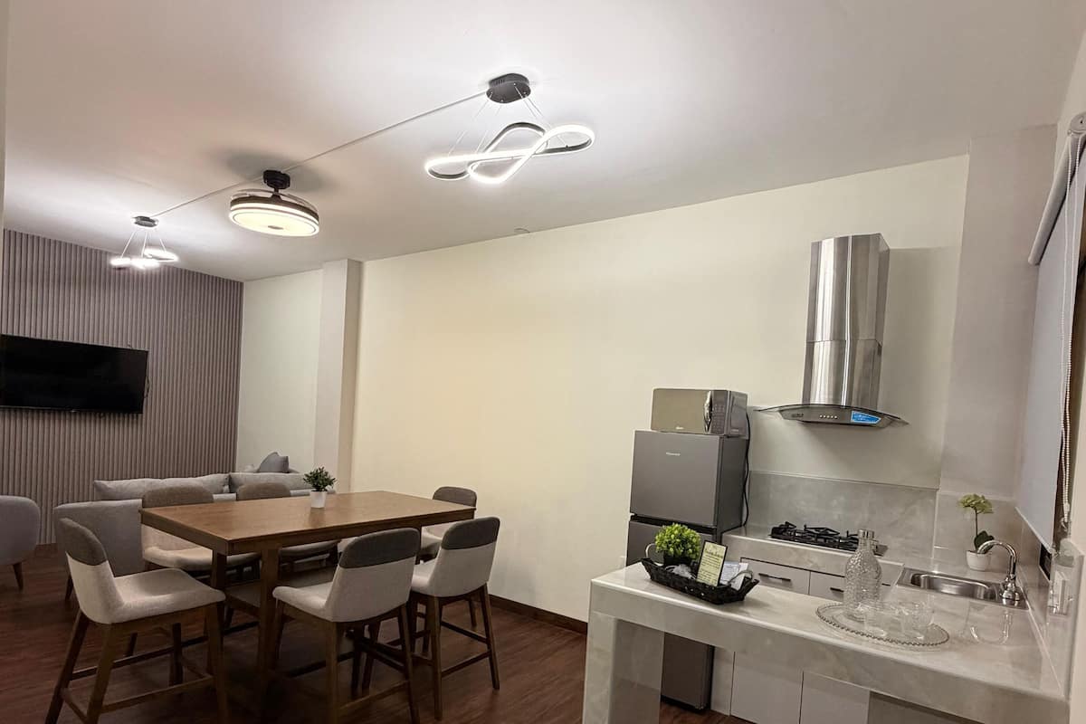 A modern kitchen with a dining area, featuring a wooden table, chairs, and a built-in oven.