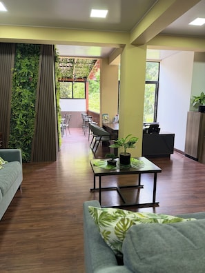 A modern interior with a long dining table, chairs, a sofa, and a coffee table with plants. - Villa Las Flores (San Salvador)