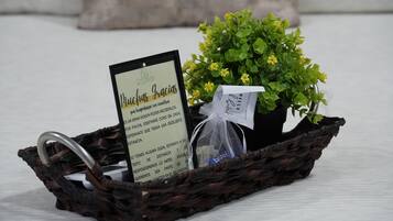 Una cesta de mimbre que contiene una pequeña planta en maceta con flores amarillas, una tarjeta con texto y una bolsa de plástico.