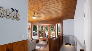 Un interno in legno con una scala, un divano e una vista attraverso ampie finestre.