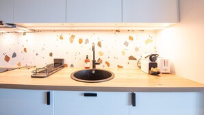 A kitchen with a modern design, featuring a black sink, a toaster, and a countertop with a unique terrazzo backsplash. - Valencio - Superb cosy apartment (Lyon)
