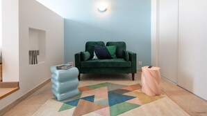 A living room with a green sofa, a blue ottoman, and a multicolored rug. - Valencio - Superb cosy apartment (Lyon)