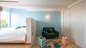 A bedroom with a bed, a green armchair, a small table, and a patterned rug. - Valencio - Superb cosy apartment (Lyon)