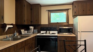 Una cocina con armarios de madera, estufa, microondas y ventana con vistas.
