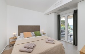 Une chambre d’hôtel avec un grand lit, une table de chevet, une lampe et une vue sur l’extérieur.