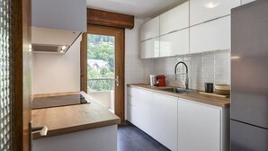 A modern kitchen with white cabinets, a wooden countertop, and a stainless steel refrigerator.