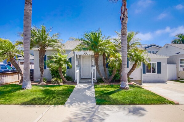 A residential house with a front yard, palm trees, and a driveway.