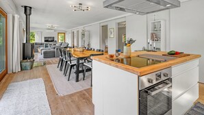 Eine moderne Küche mit einer zentralen Kochinsel, einem eingebauten Backofen und einer großen Dunstabzugshaube.