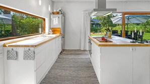 Eine moderne Küche mit großem Fenster, Einbauofen und Blick auf den Garten.