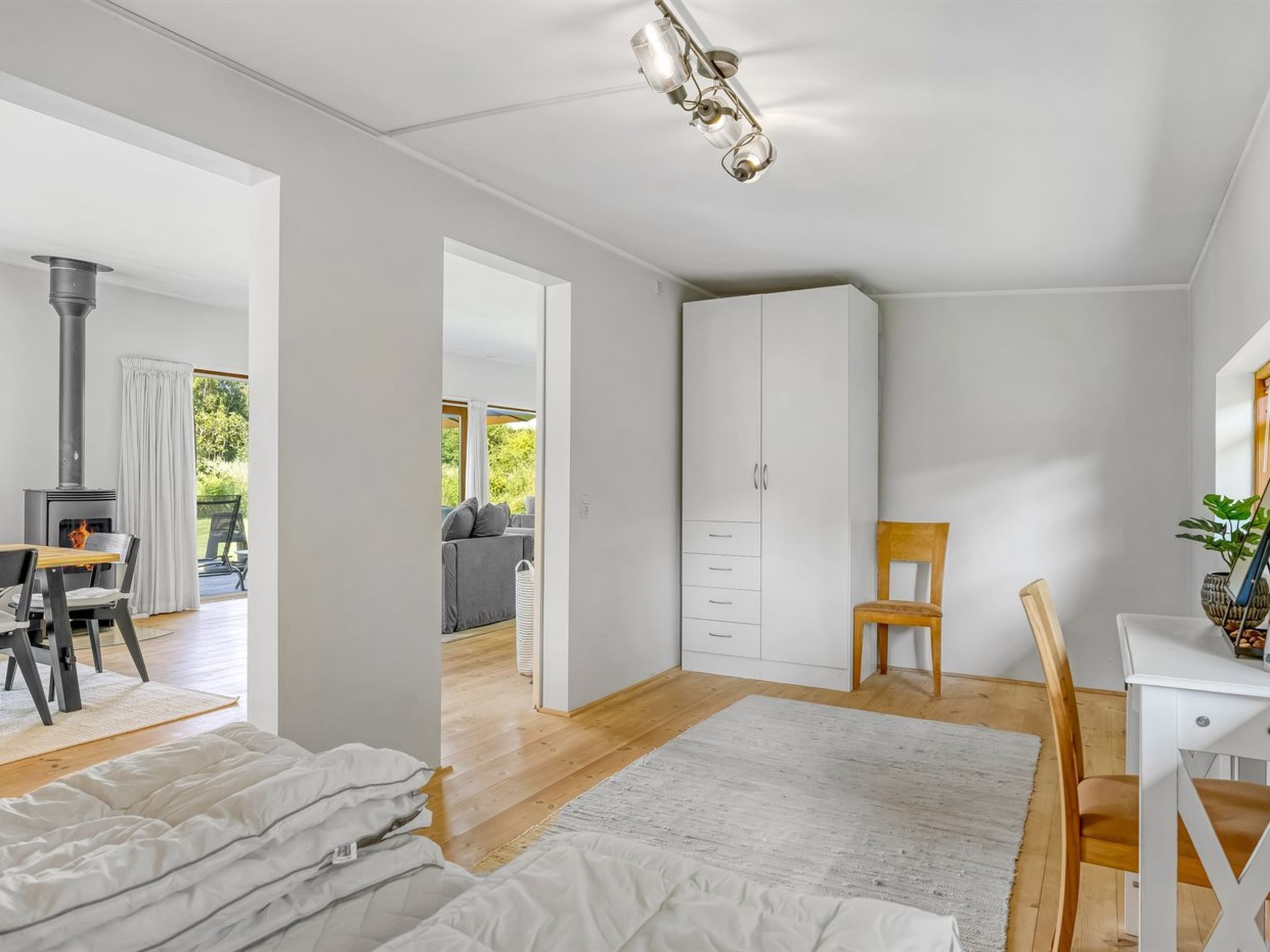 Ein modernes Zimmer mit Bett, Schreibtisch, Stuhl und Kleiderschrank. Es gibt ein Fenster mit Vorhängen, eine Deckenleuchte und einen Kamin.