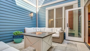 Eine Terrasse mit Feuerstelle, Korbmöbeln und einem Topfpflanzen.