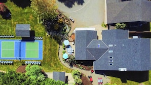 Vista aérea de una zona residencial con cancha de tenis, un patio cubierto y varias casas.