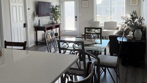 Un grand espace de vie comprenant une table et des chaises de salle à manger, un canapé et un téléviseur.