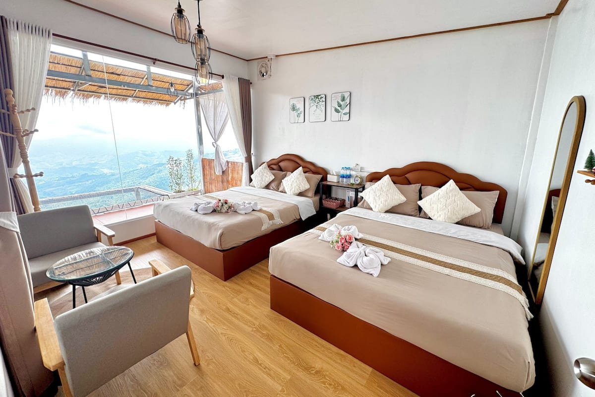 Une chambre d’hôtel avec deux lits, une petite table, une chaise et une vue sur le paysage.