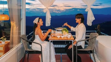 Ein Balkon mit Tisch für Zwei, mit Blick auf eine Berglandschaft.