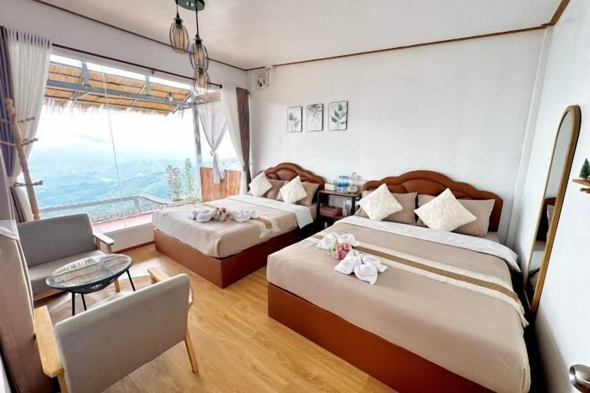 Une chambre dâhĂŽtel avec deux lits, un balcon, un bureau et une vue sur le paysage.